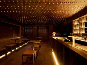 A dimly lit restaurant bar with a barrel backdrop featuring a wooden ceiling and decor.