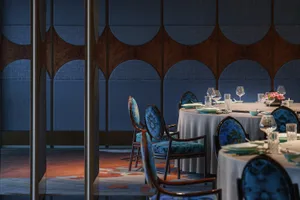 A modern restaurant interior with blue upholstered chairs and textured fabric walls