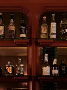 Modern bar shelves with a wooden finish, showcasing a variety of liquor bottles.