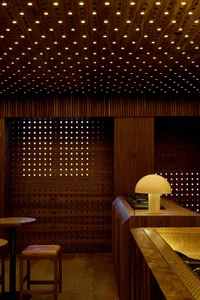 A modern bar interior with wooden finishes and a mushroom-shaped lamp on the counter.