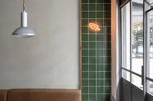 Modern cafe interior featuring green tiled wall and hanging light fixture