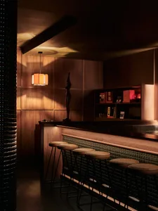 Modern retail bar with wooden panels, leather stools, and metal accents.