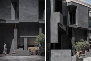 Concrete restaurant exterior with outdoor seating and greenery.