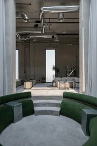 Industrially designed office lounge with concrete floor and green textile seating