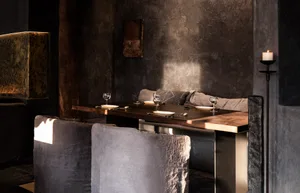 Industrial-themed restaurant interior with metallic table, wooden accents, and textured fabric seating.