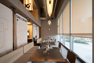 A modern industrial restaurant with metallic furniture, large windows, and minimalist decor.