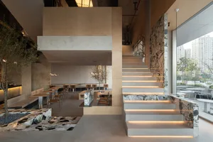 Modern restaurant interior with concrete walls, marble countertops, and bamboo seating.