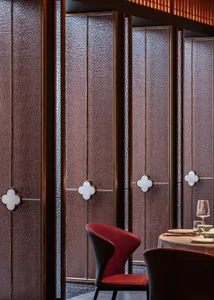 A modern restaurant interior featuring glazed glass panels and a red upholstered chair.