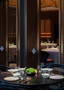 A modern restaurant interior with black and white tables, wooden accents, and greenery.