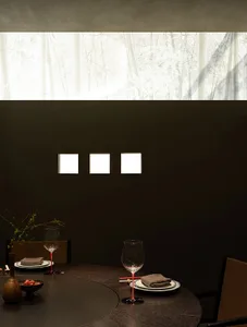 A minimalist dining room features a wooden table with chairs and a vase, under a large window with a bamboo forest view.