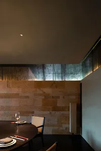 極簡室內設計，搭配磚牆與石材牆面，擺放圓形餐桌與餐椅。