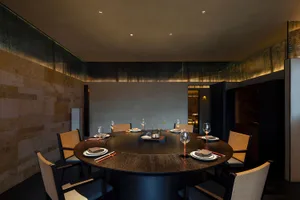 A circular dining table set for dinner with wooden chairs and elegant place settings.