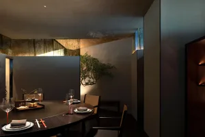 Circular dining table surrounded by chairs in a minimalist restaurant setting.