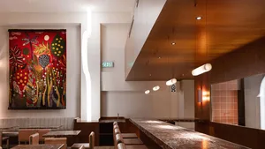 Modern cafe interior featuring wood-paneled walls, marble countertops, and colorful mural on the wall.
