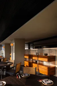 The interior of a modern restaurant featuring minimalist design in wood, glass, and wicker materials.