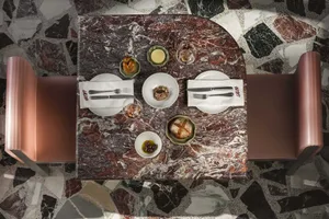 A restaurant table with a marble tabletop, set with plates, cutlery, and bread.