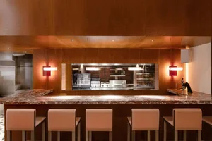 A modern minimalist restaurant bar with a marble countertop and stools.