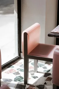 A modern pink metal cafe chair with a minimalistic design.
