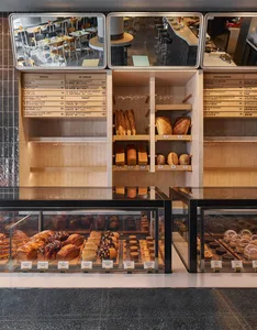 A bakery storefront with shelves displaying various breads and pastries, wood shelves, glass display cases, and ceramic tiles