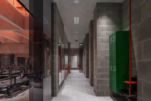 Interior view of a gym with industrial-style brick walls, concrete floor, and glass partitions.