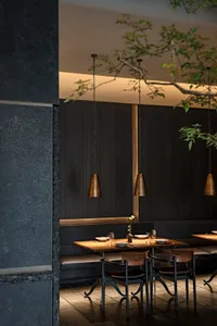 Industrial style restaurant dining room with black metal pendant lights, wooden tables, and leather seats.