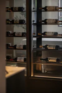 A minimalist wine cellar with black glass shelves containing bottles of wine.