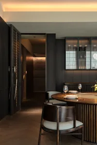 Modern dining room with walnut wood furniture and dark wooden paneling.