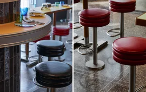 Modern restaurant interior featuring black and red bar stools with metal and plastic frames and leather seats.