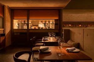 Modern restaurant interior with a counter made of brass and wood, against a brick wall