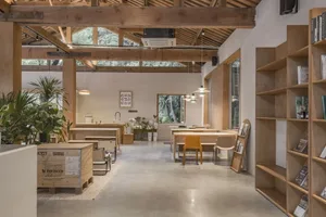 Modern industrial coffee roastery office space with wooden tables, concrete floor, and exposed wooden beams