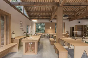 A modern cafe interior with wooden furniture and a long central table.
