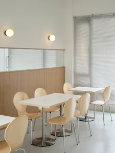 A modern cafe interior with wooden furniture and white tables.