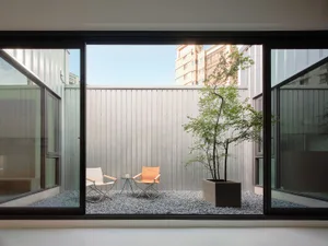 Modern minimalist outdoor space featuring a metallic wall and gravel ground.