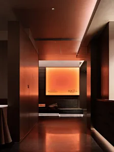 A minimalist bathroom with metallic surfaces and a glowing orange light panel.