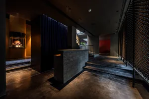 A sleek, modern hotel lobby featuring concrete, glass, and metal materials.