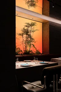 A modern restaurant interior featuring indoor plants and natural materials.