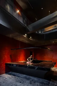 A modern restaurant kitchen with a black marble countertop and red walls.