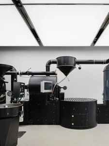 Black industrial coffee roasting machine with metallic components and a digital control panel.