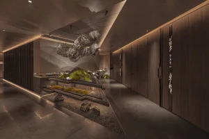 Modern minimalist hotel corridor featuring wooden walls and a rock garden.