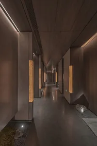 A minimalist hotel corridor with wooden walls and concrete flooring.