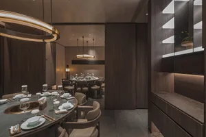 A modern minimalist restaurant interior featuring marble countertops, wooden tables, and glass accents.
