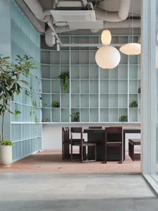 A modern office cafe space featuring a glass wall, concrete floor, and wooden furniture.