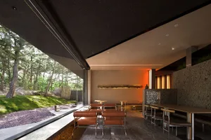 A modern restaurant interior with concrete walls and natural wood accents.