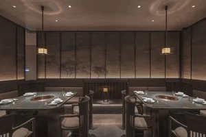 Modern restaurant interior with dark oak tables, white fabric seating, and minimalist lighting