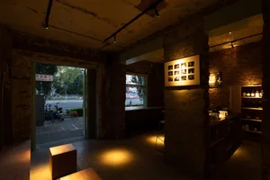Interior of a cozy, industrial-style cafe-bar with exposed brick walls, concrete flooring, and dim lighting.