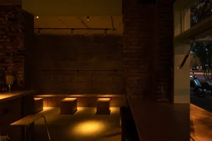 Interior of a restaurant bar featuring industrial design elements such as brick walls and concrete flooring.