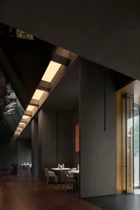 Contemporary restaurant interior with concrete, brass, and glass materials.