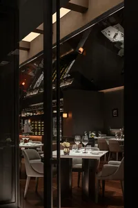 Modern restaurant interior with glass walls and tables.