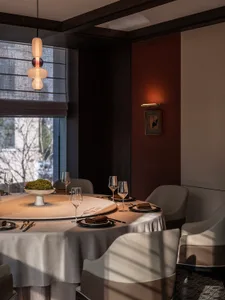 A modern restaurant interior with a round table, chairs, and decorative lighting.