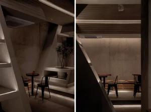 A cozy minimalist restaurant interior with concrete walls and modern lighting.